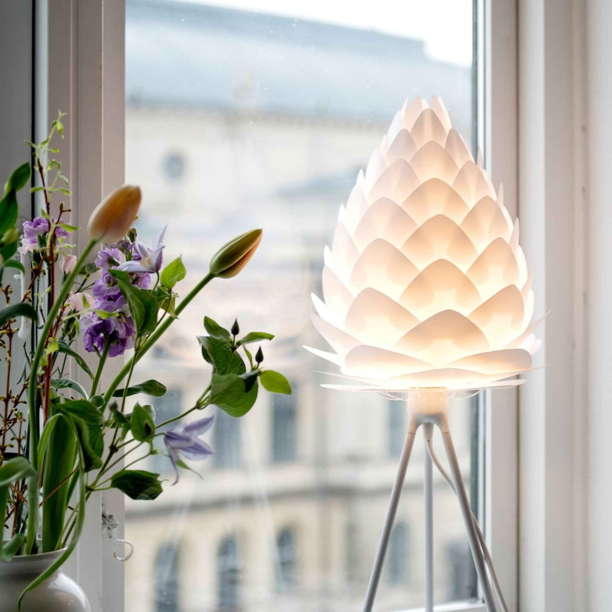 UMAGE Conia gulvlampe i Pearl White på hvid Tripod floor ved et skrivebord
