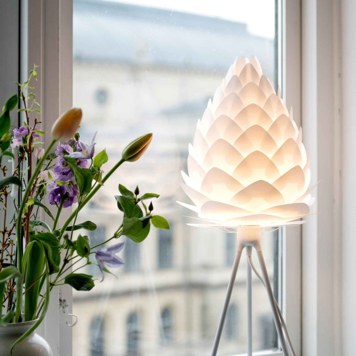 UMAGE Conia gulvlampe i Pearl White på hvid Tripod floor ved et skrivebord