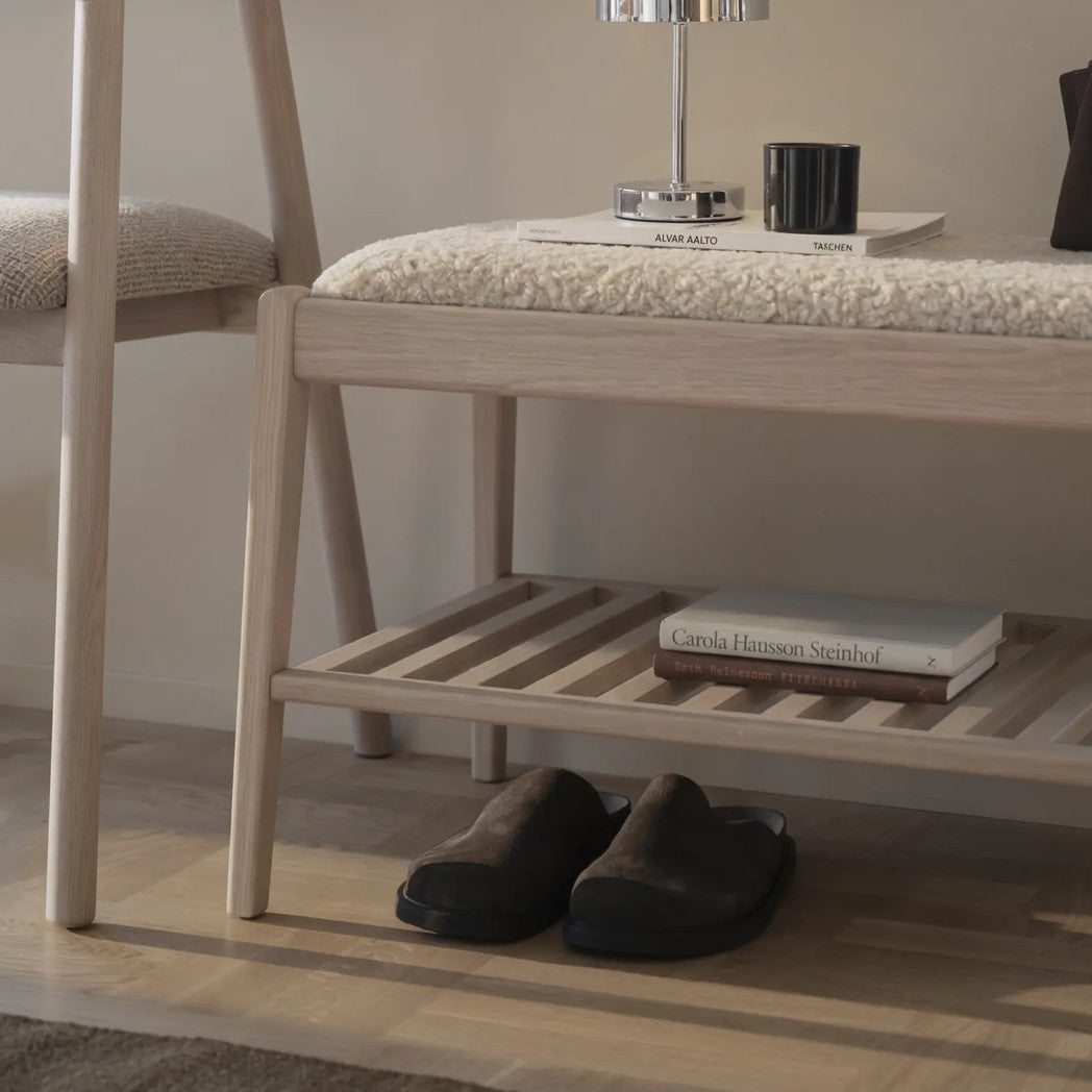 Nærbillede af Rowico Garrick bænk i hvidpigmenteret eg med sæde i beige fåreskindslook og hylde