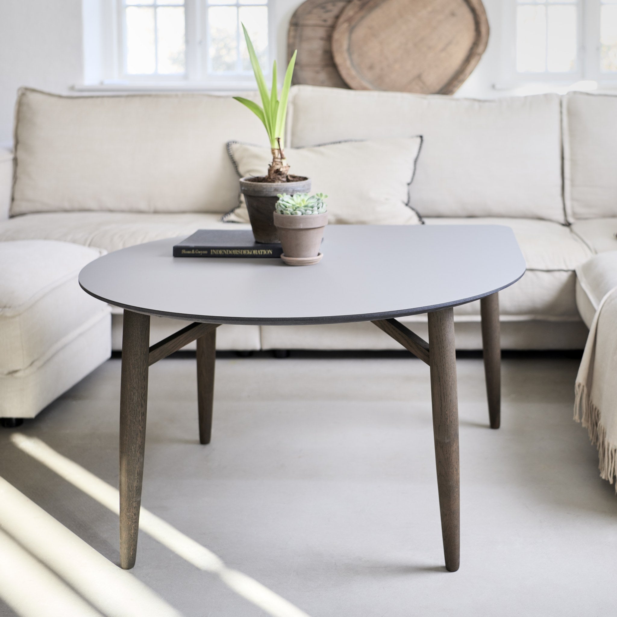 Thomsen Furniture Katrine sofabord, Baloon i grå laminat med røgfarvede egeben foran lys sofa