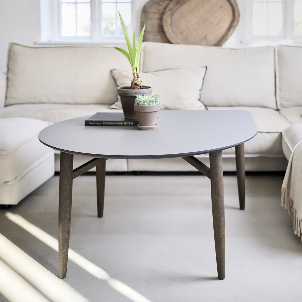 Thomsen Furniture Katrine sofabord, Baloon i grå laminat med røgfarvede egeben foran lys sofa